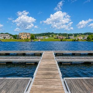 deep-creek-dock-section-2 | Swack Vacations Wooden dock extending into a lake, with houses across the water and a bright blue sky with clouds.