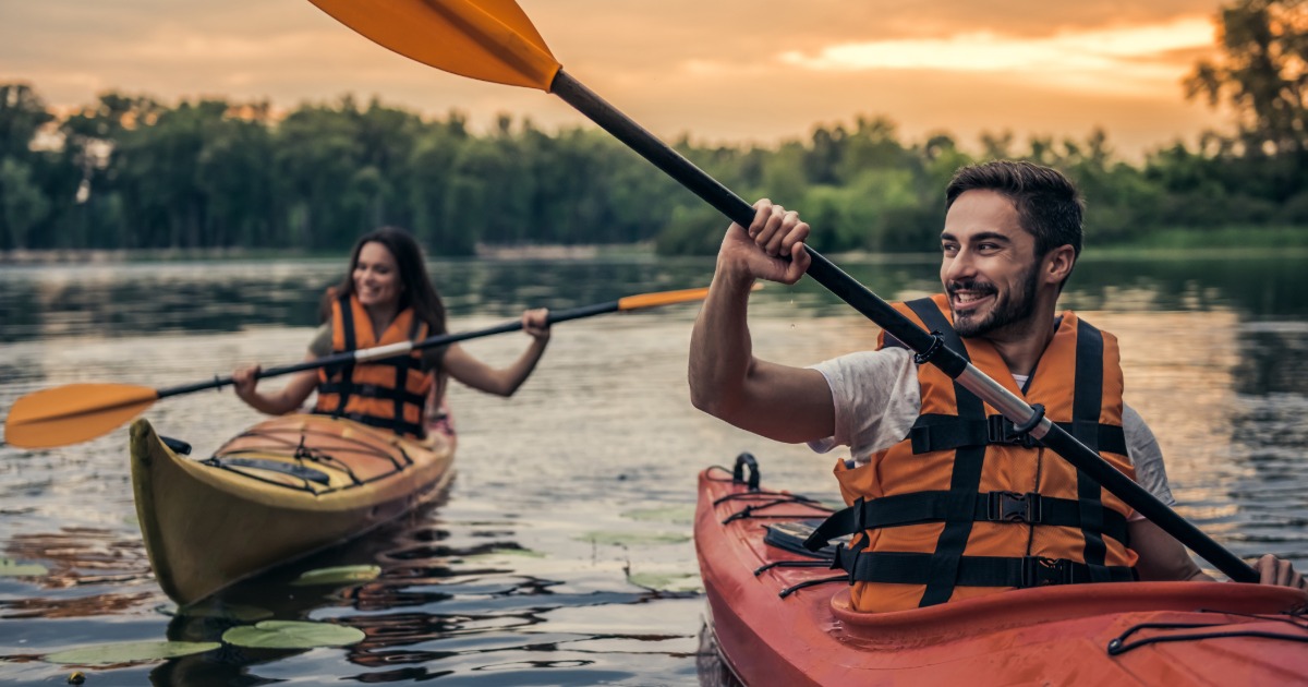 Family kayaking on Deep Creek Lake, Maryland, on a clear summer morning with tree-covered hills in the background