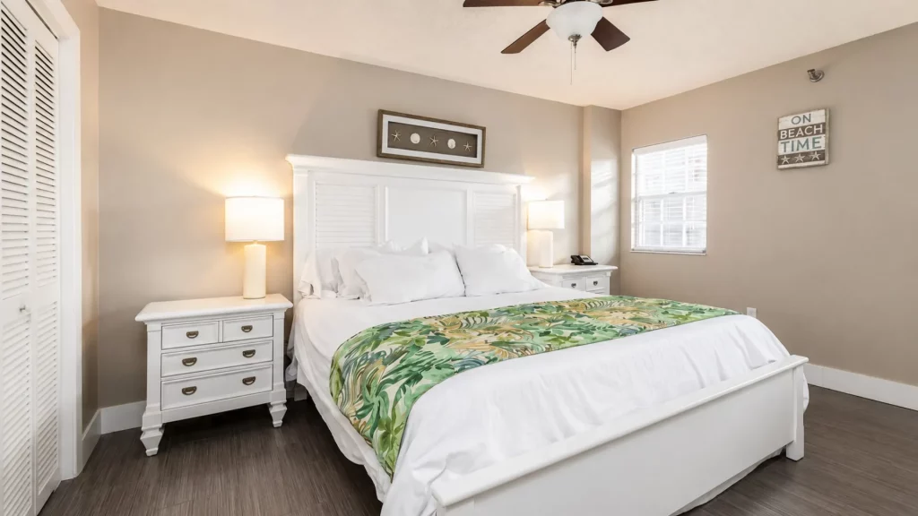 Bright coastal bedroom with a white bed frame, twin nightstands, and a tropical green blanket.