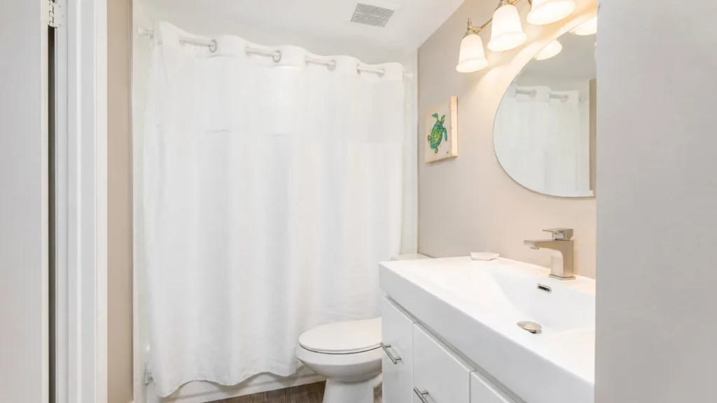 Modern white bathroom vanity with oval mirror, rectangular sink, and brushed-nickel faucet; white shower curtain in the background
