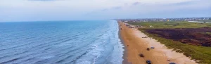 Serene beach in Texas with cars pulled up to the shore