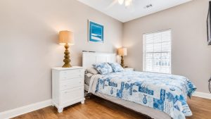 407-bottom-floor-queen | Swack Vacations Bedroom with a white headboard and two matching nightstands, blue patterned quilt, and warm lamps on each side.