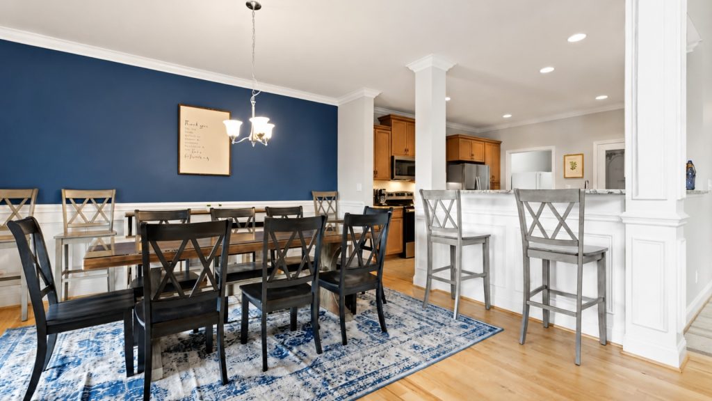 Dining area with dark wood table and black chairs, blue accent wall, and light chandelier above.