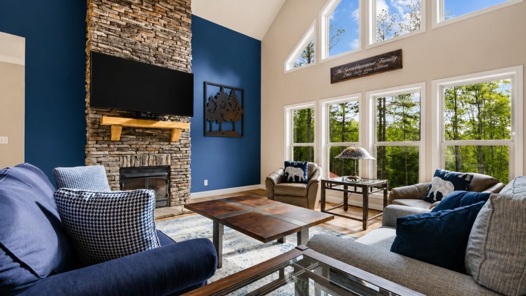 Living room with a stacked-stone fireplace, a mounted TV, and a blue accent wall.