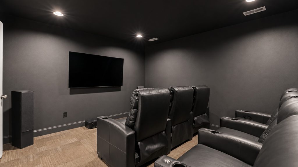 Home theater with a wall-mounted flat-screen TV and black leather recliner seating.