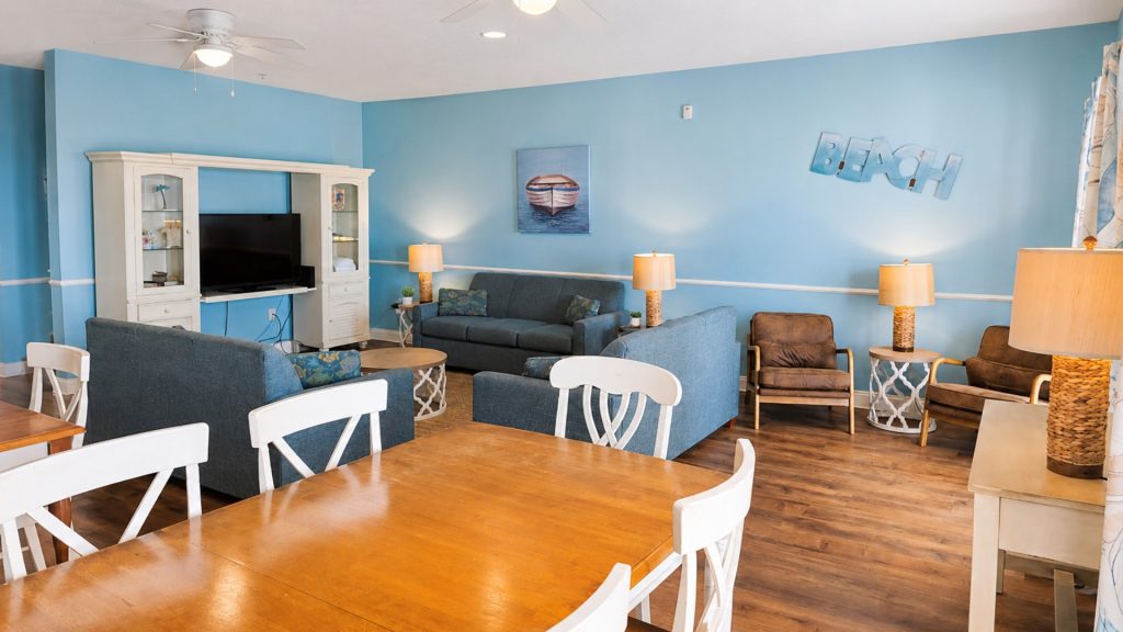 Bright beach-themed living room with blue walls, white entertainment cabinet, and blue sofas.