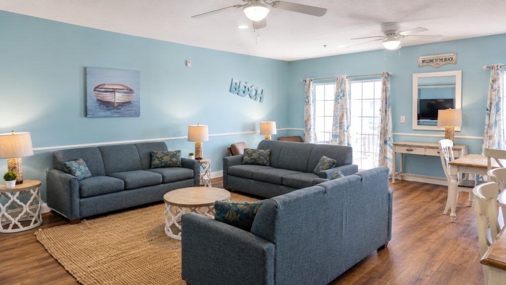 Cozy beach-themed living room with blue sofas, matching cushions, and a woven jute rug.