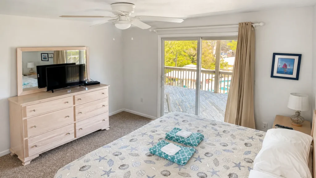 Bedroom featuring a light wood dresser with a large mirror, and a TV on top facing the bed/room.