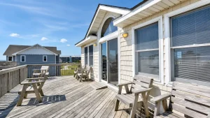 rio-top-balcony | Swack Vacations Wooden deck with several weathered chairs overlooking a coastal neighborhood on a sunny day.