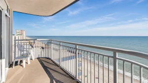 southern-breeze-2-ocean-view | Swack Vacations Balcony with a white plastic chair overlooking a sandy beach and blue ocean under a clear sky to the horizon.