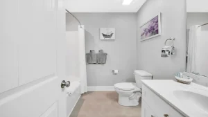 whipering-winds-slider-images 10 | Swack Vacations Modern gray bathroom with white tub, shower curtain, toilet, and vanity opposite.
