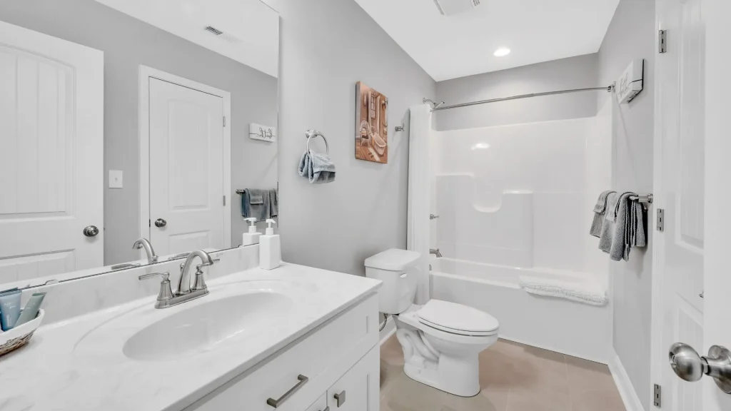 Modern white bathroom with a double-sink vanity, gray walls, and a white tub/shower combo with a curtain.