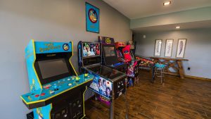 Arcade room filled with classic upright machines, including The Simpsons and Star Wars cabinets, along a wall.