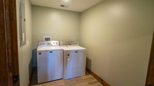 Laundry room with a white washer and dryer side by side against pale green walls.