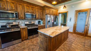 Rustic kitchen with dark wood cabinets, stainless steel appliances, and a marble island.
