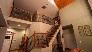 Interior view of a multi-level staircase with wooden handrails and black iron balusters in a spacious living area