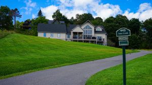 Rental house on a grassy hill with a 442 Lazy Creek sign in the foreground.