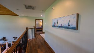 Upper-floor hallway with a wooden railing and a large sailboat artwork on the right wall.