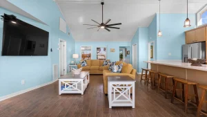 Living room with light blue walls, brown hardwood floor, and a large wall-mounted TV on the left.